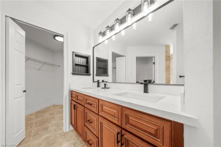 Full bathroom with double vanity and a spacious closet