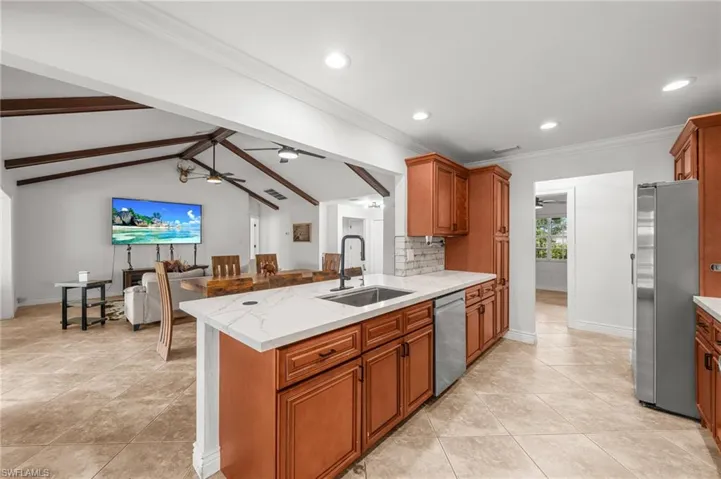 Kitchen with brown cabinetry, appliances with stainless steel finishes, light stone counters, recessed lighting, and tasteful backsplash