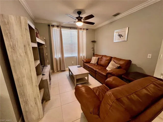 Living area featuring crown molding, a ceiling fan, and light tile patterned floors