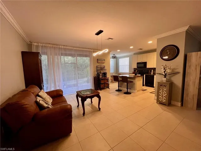 Living room featuring crown molding and light tile patterned floors
