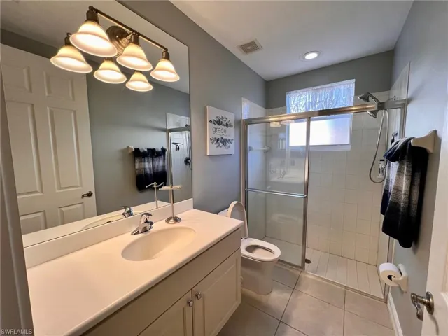 Full bath featuring vanity, a stall shower, and light tile patterned floors