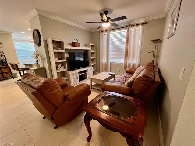 Living room featuring crown molding, a ceiling fan, light tile patterned floors, and healthy amount of natural light