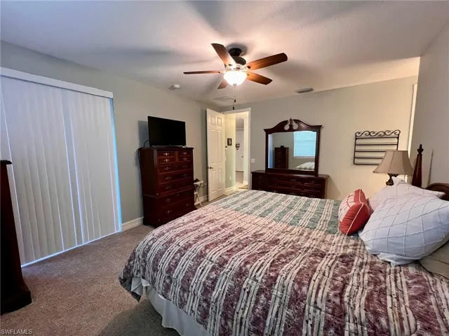 Carpeted bedroom with a ceiling fan and baseboards
