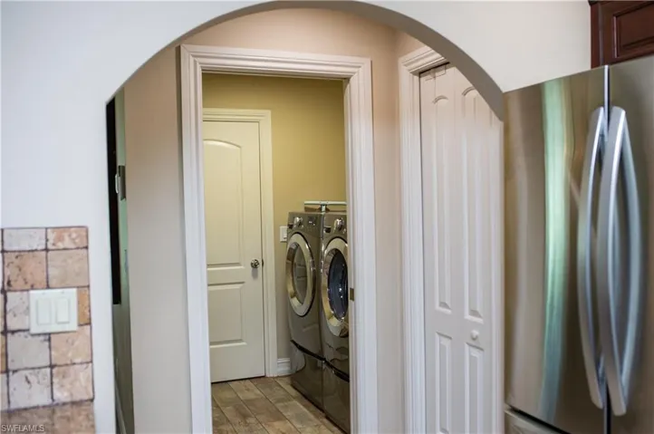 View from kitchen with arched walkways leading to laundry room with washing machine and clothes dryer