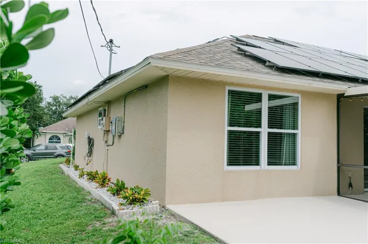 View of home's exterior with stucco siding, solar panels, and side yard