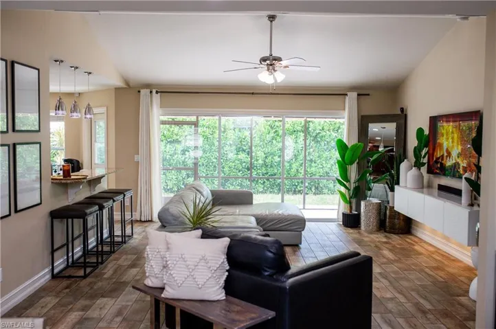 Living area featuring lofted ceiling, a ceiling fan, and wood tile finished floors