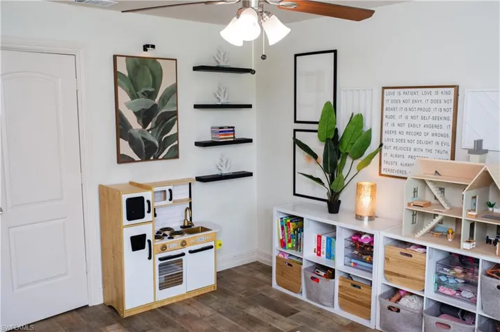 Recreation room featuring a ceiling fan and dark wood-style floors