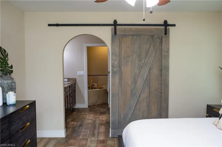 Bedroom featuring wood-like tile flooring, a ceiling fan, and master bath