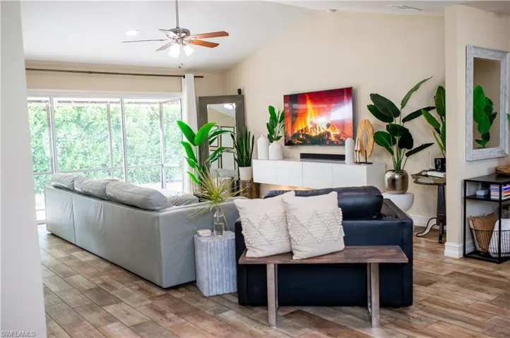 Living room with vaulted ceiling, wood tile finished floors, and a ceiling fan