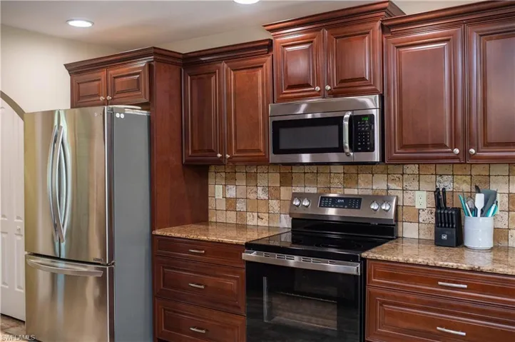 Kitchen featuring appliances with stainless steel finishes, granite counters, and backsplash
