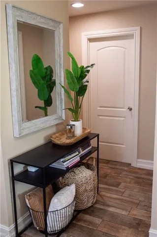 Hallway with wood-style tile leads to 2 bedrooms and bath
