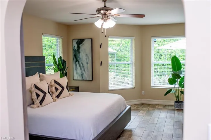 Bedroom featuring arched walkways, light wood-type tile flooring, and a ceiling fan