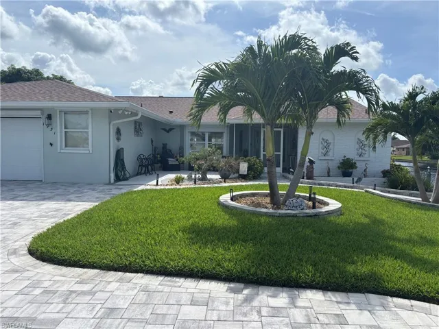 Ranch-style house featuring a front yard, stucco siding, decorative driveway, and an attached garage