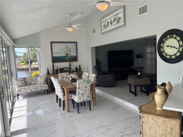 Dining space featuring ceiling fan, lofted ceiling, and marble finish floors
