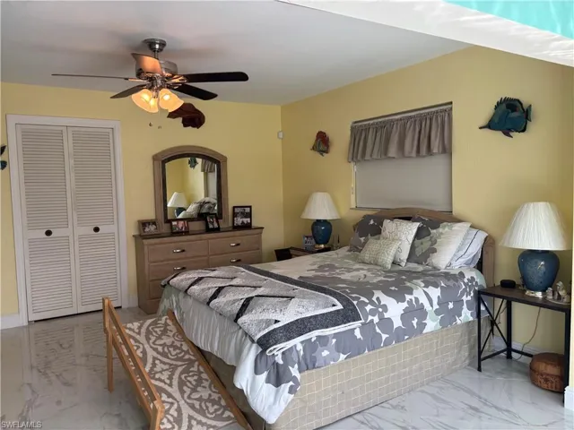 Bedroom with marble look tile flooring, a closet, and ceiling fan