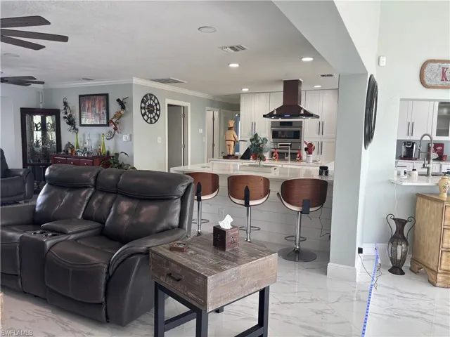 Living room featuring light marble finish floors, ceiling fan, crown molding, and recessed lighting