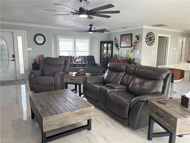 Living room with light marble finish floors, ceiling fan, and crown molding
