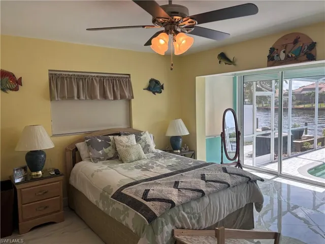Bedroom featuring marble finish flooring, access to exterior, a water view, and ceiling fan