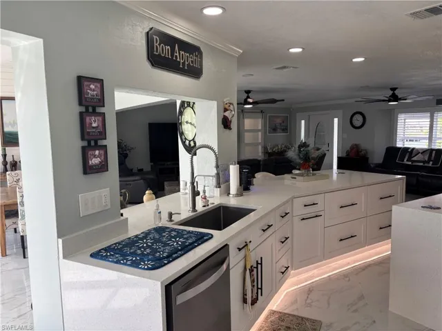 Kitchen featuring ceiling fan, stainless steel dishwasher, light marble finish floors, open floor plan, and recessed lighting