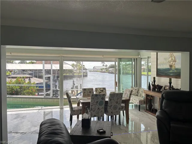 Dining space featuring crown molding, healthy amount of natural light, a water view, marble tiled flooring, and a textured ceiling