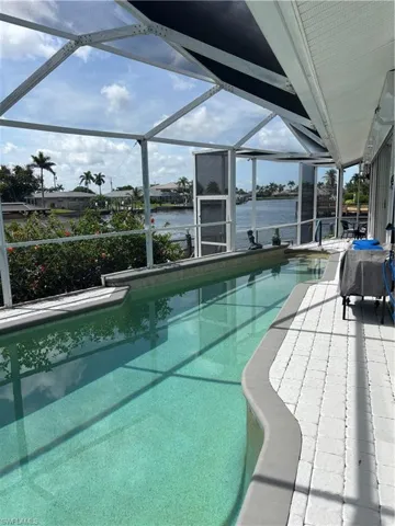 Outdoor pool featuring a water view, a patio, and a lanai
