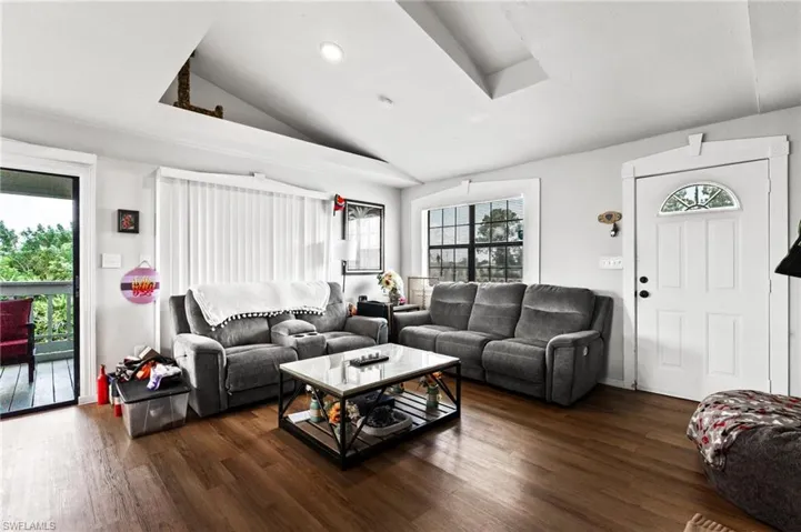 Living room with plenty of natural light, dark hardwood / wood-style floors, and lofted ceiling