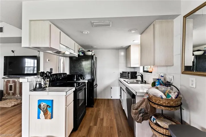 Kitchen with sink, appliances with stainless steel finishes, dark hardwood / wood-style flooring, and tasteful backsplash