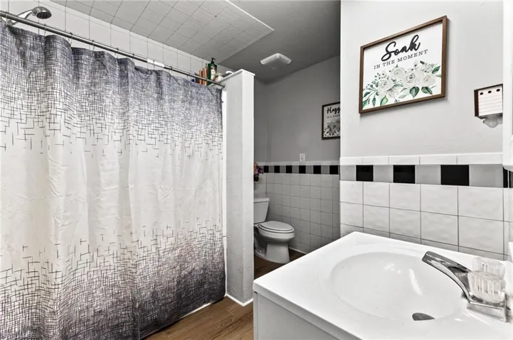 Bathroom featuring vanity, toilet, wood-type flooring, and tile walls