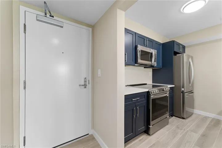 Kitchen featuring appliances with stainless steel finishes, blue cabinetry, and wood tiled floors