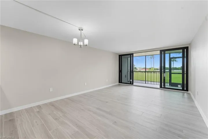 Spare room featuring light wood finished floors, a chandelier, and floor to ceiling windows
