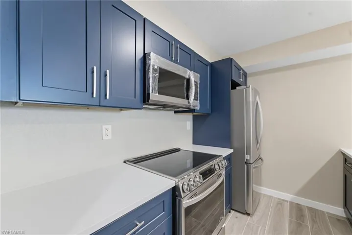 Kitchen featuring appliances with stainless steel finishes, blue cabinetry, and wood finish floors