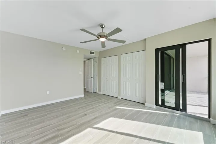 Unfurnished bedroom featuring two closets, wood finish floors, access to exterior, and a ceiling fan