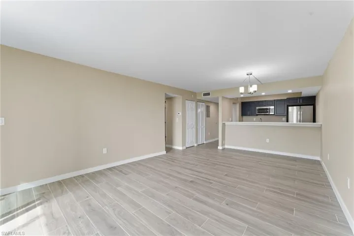 Unfurnished living room featuring a chandelier and light wood-type flooring