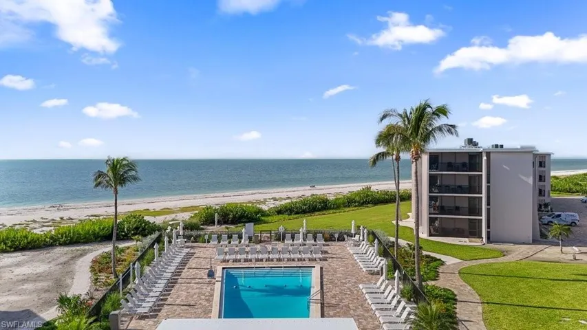 Community pool featuring view of water and beach and a patio