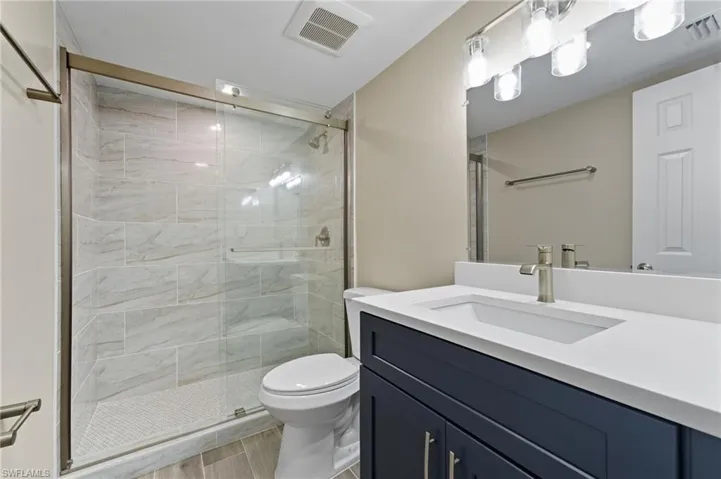 Bathroom with vanity, a shower stall, and light wood-style flooring