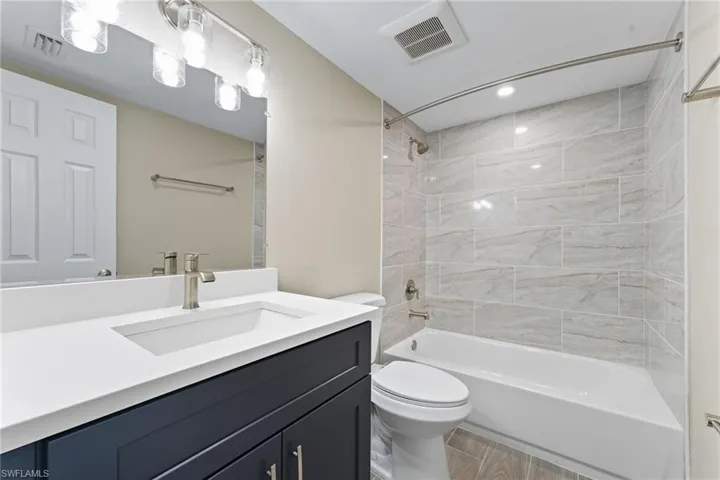 Bathroom featuring shower / washtub combination, vanity, light wood-type flooring, and recessed lighting