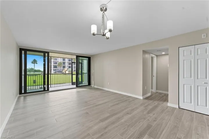 Unfurnished living room with expansive windows, light wood-style flooring, and a chandelier