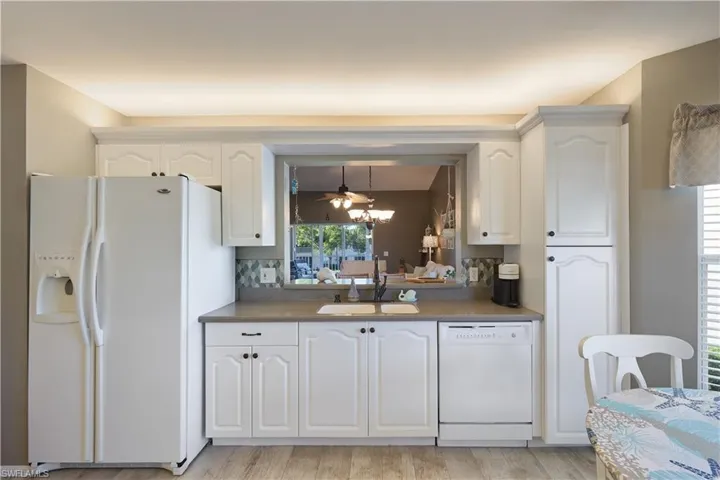 Kitchen featuring white cabinets, white appliances, plenty of natural light, and sink