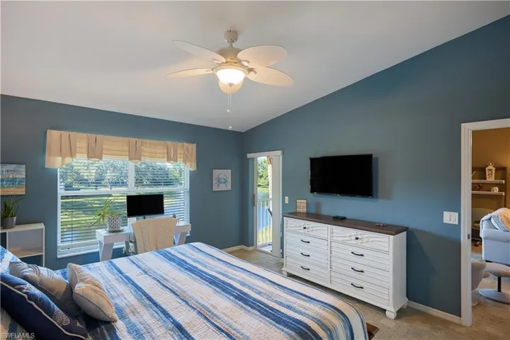 Bedroom with lofted ceiling, access to outside, ensuite bathroom, ceiling fan, and light colored carpet