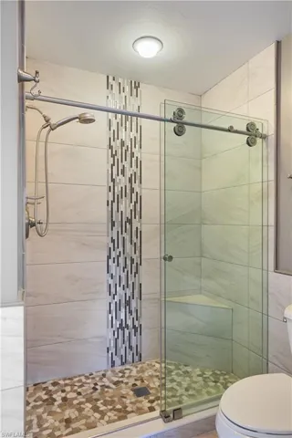 Bathroom with toilet, walk in shower, and tile walls