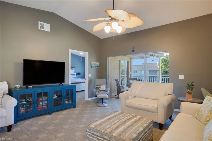 Living room with light carpet, ceiling fan, and vaulted ceiling
