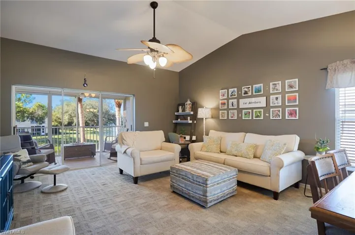 Carpeted living room with ceiling fan and lofted ceiling