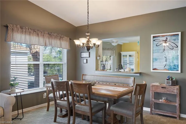 Carpeted dining area featuring ceiling fan with notable chandelier