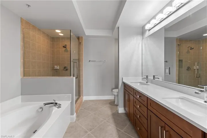 Full bathroom featuring double vanity, plus walk in shower, toilet, and tile patterned floors