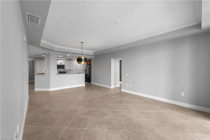 Living room with crown molding, a tray ceiling, and light tile patterned floors