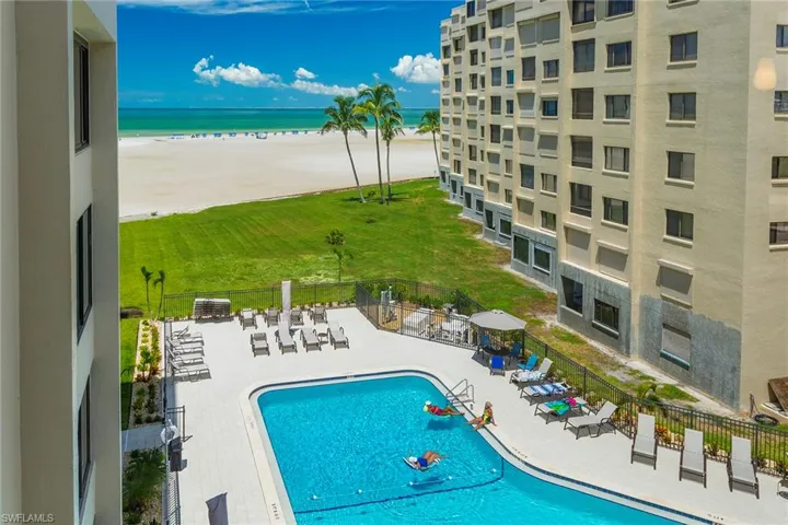 Community pool with view of water and beach and a patio area