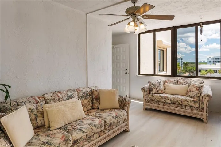 Living room with a textured wall, wood finished floors, and a ceiling fan