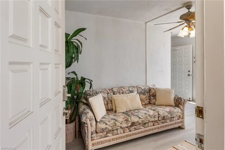 Sitting room with ceiling fan, wood finished floors, and a textured wall