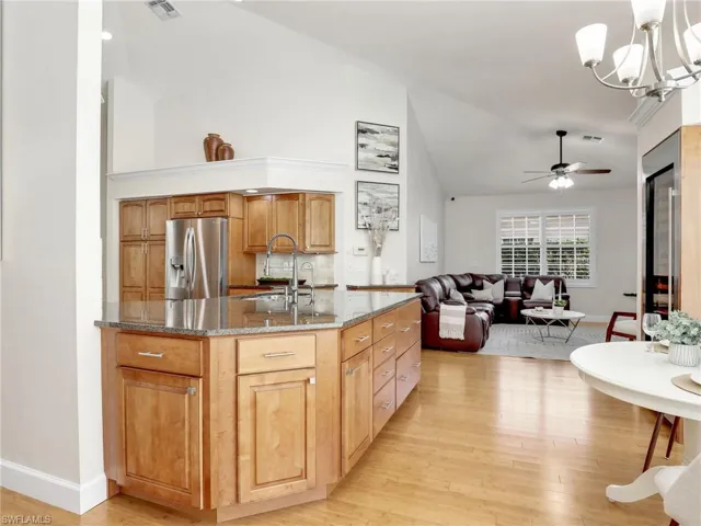 Kitchen with high vaulted ceiling, stainless steel appliances, backsplash, and light hardwood / wood-style floors