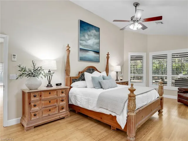 Bedroom with ceiling fan, light wood-type flooring, multiple windows, and lofted ceiling